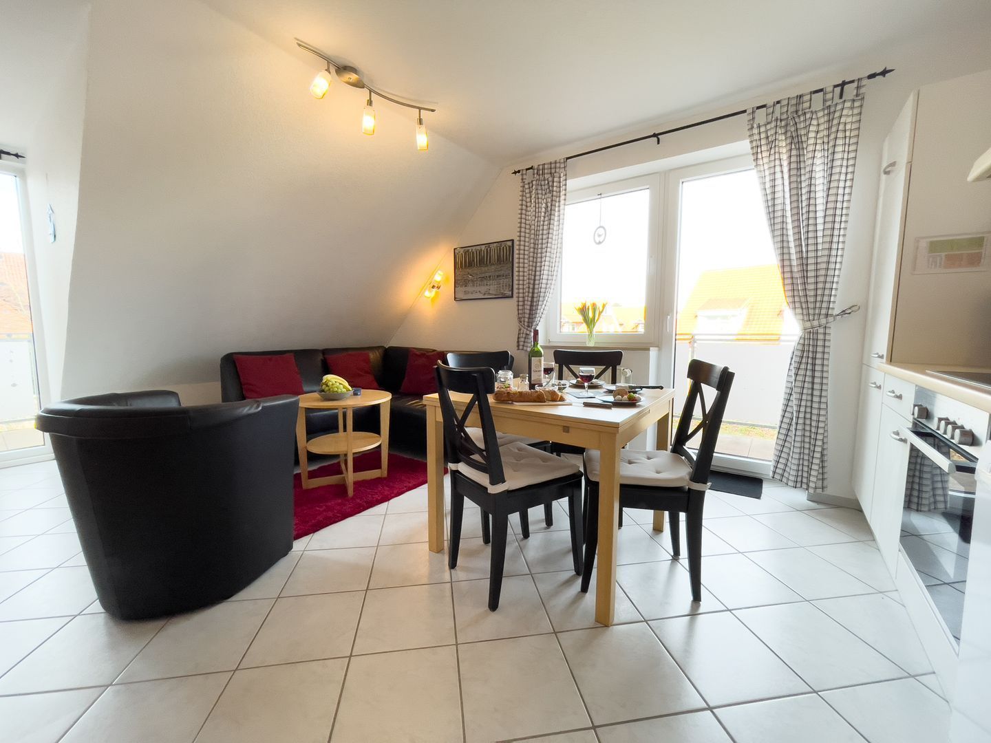 Ein modernes Wohnzimmer mit Esstisch, schwarzen Stühlen, einer schwarzen Couch und einem roten Teppich. Ein Fenster mit Vorhängen bietet einen Blick ins Freie.