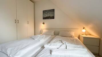 A bedroom with a bed, two bedside tables, a nightstand, and a wardrobe.