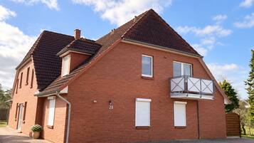 Ein zweigeschossiges Backsteinhäuschen mit Balkon und Hausnummer 28, sowie einer gepflasterten Auffahrt.