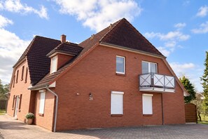 A two-story brick house with a balcony, a number 28 sign, and a paved driveway.