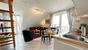 A modern kitchen with a sink, dining area, and a staircase. - Hamburger Straße 28 - Apartment Jonathan in the spa town of Sahlenburg (Cuxhaven)