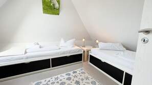 Une chambre avec deux lits, une petite table de chevet avec une lampe et un tableau accroché au mur.