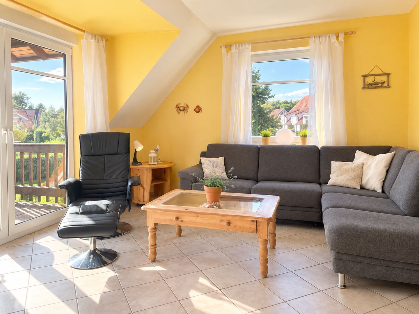 Ein Wohnzimmer mit einer Couch, einem Sessel und einem Couchtisch, ein Balkon mit Blick und einer gelben Wand.