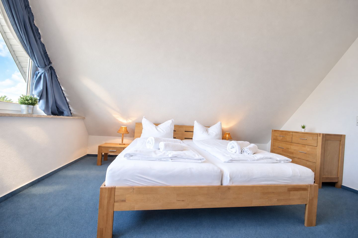 Ein Schlafzimmer mit einem hölzernen Bett, zwei Nachttischen, einer Kommode und einem Fenster mit Vorhängen.