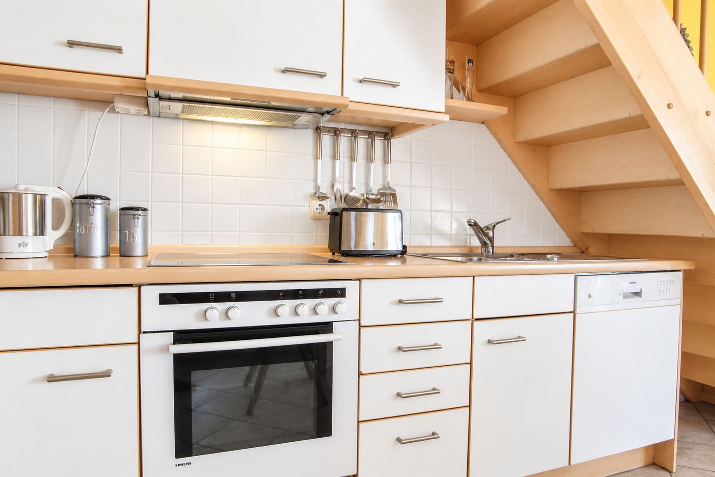 Eine Küche mit weißen Schränken, einem Backofen, einem Kochfeld und einer Spüle.