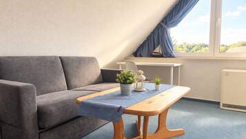 Ein modernes Zimmer mit einem grauen Sofa, einem Holztisch und einem kleinen Topfpflanzen.