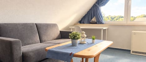 Una habitación moderna con un sofá gris, una mesa de madera y una pequeña planta en maceta.