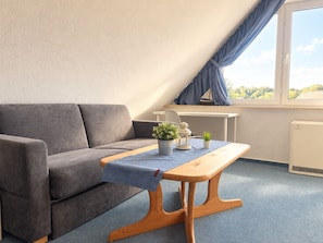 Una habitación moderna con un sofá gris, una mesa de madera y una pequeña planta en maceta.