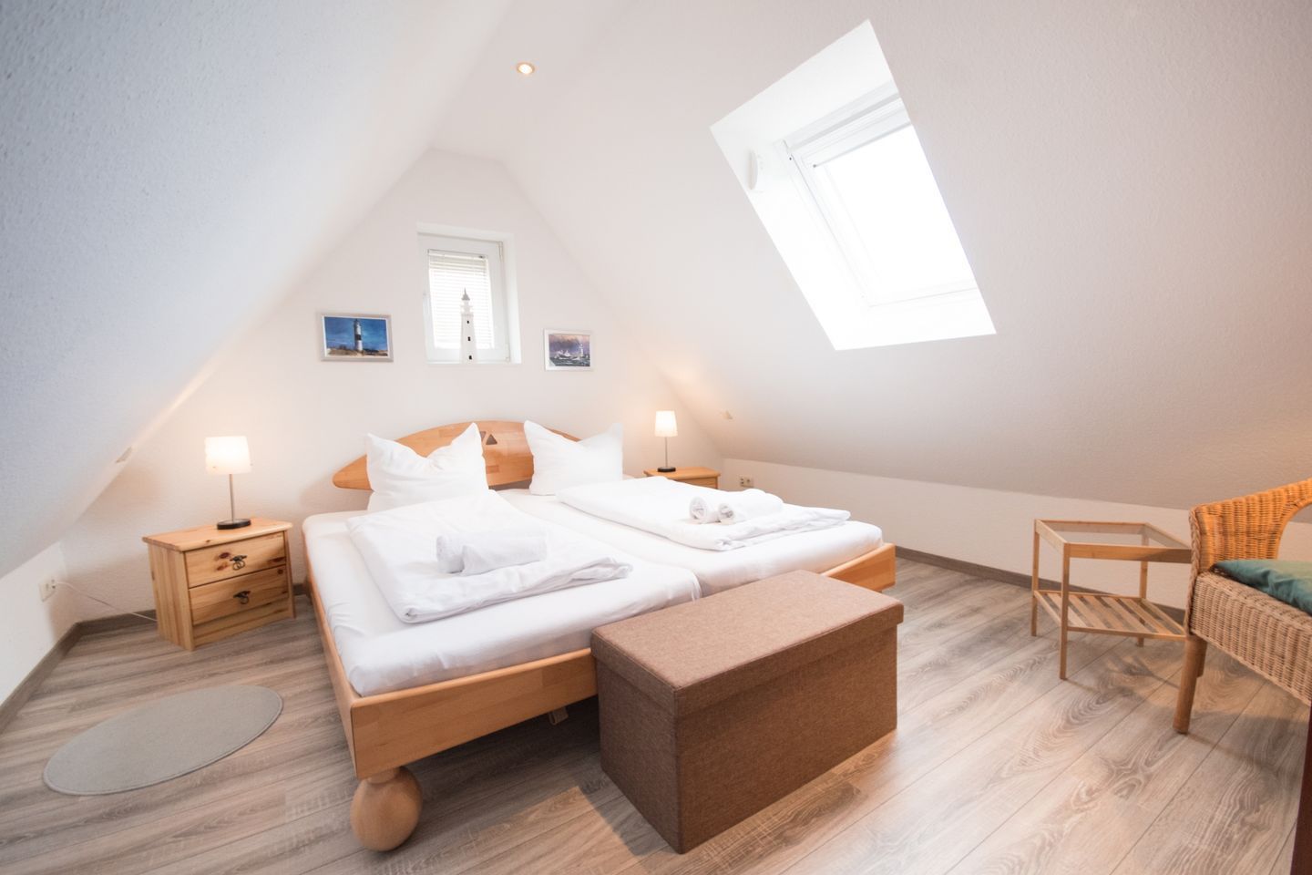 Ein Schlafzimmer mit zwei Betten, einem kleinen Tisch, einem Stuhl und einem Oberlicht.