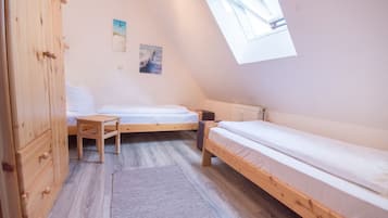 Ein kleiner, dreieckiger Raum mit zwei Holzbetten, einem Holzschrank und einem Oberlicht.