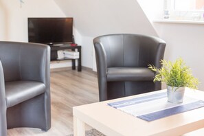 Una sala moderna con dos sillones de cuero negro, una mesa de centro de madera y una pequeña planta en maceta.