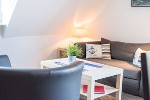Una sala de estar acogedora con un sofá, una mesa de centro y una lámpara.