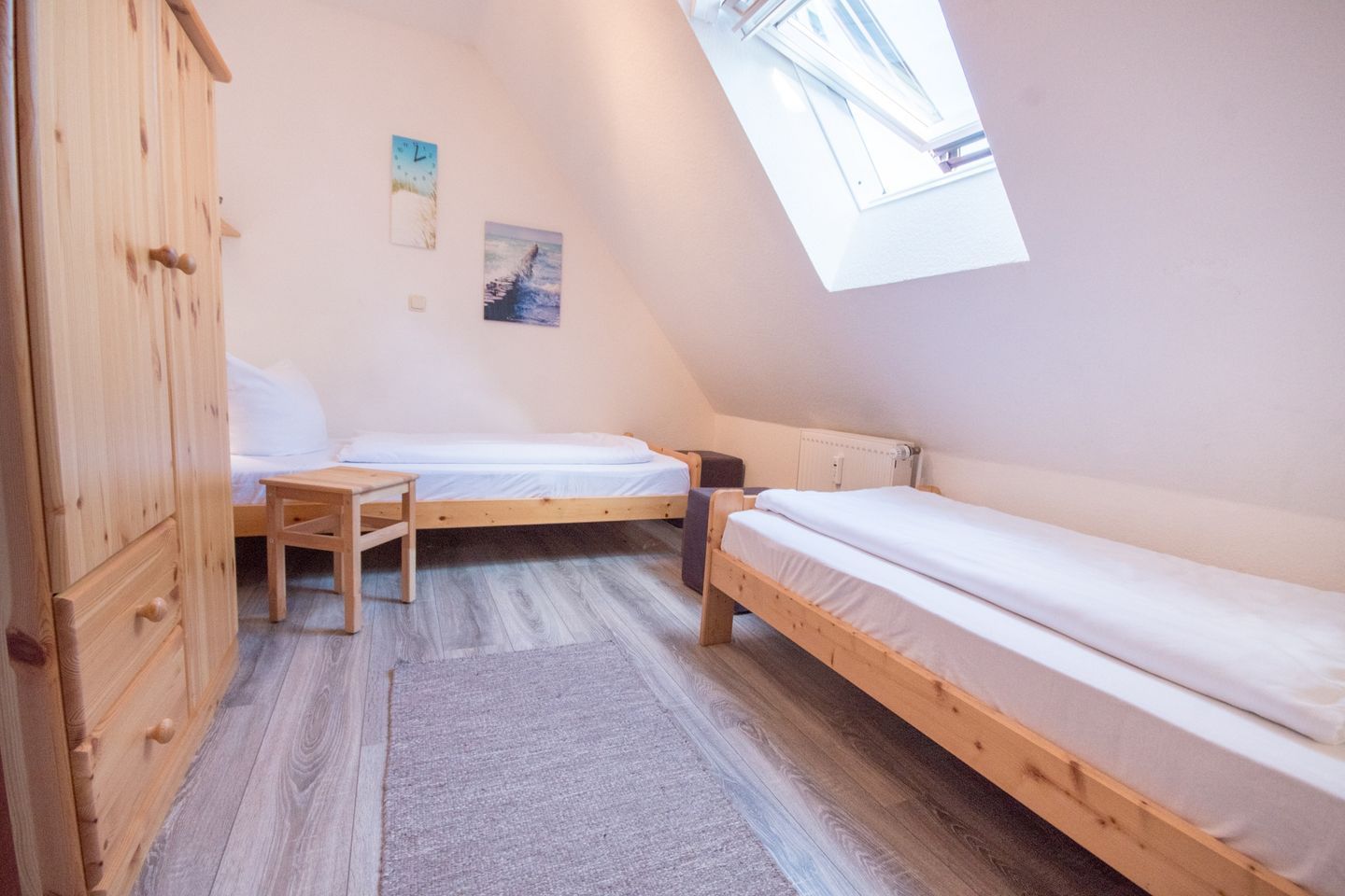 Ein kleiner, dreieckiger Raum mit zwei Holzbetten, einem Holzschrank und einem Oberlicht.