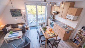 Ett kompakt bostadsutrymme med en matplats, ett litet kök och en soffa med ett soffbord.