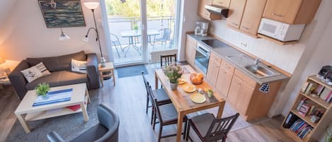 A compact living space with a dining area, kitchenette, and a sofa with a coffee table.