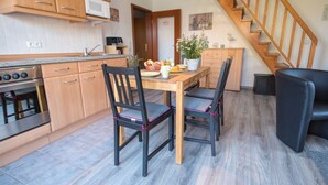 Una cucina compatta con mobili in legno, forno integrato e tavolo con sedie.