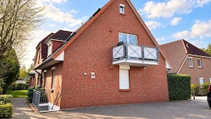 Una casa in mattoni rossi con un balcone e il numero 24 sulla parete, oltre a un vialetto lastricato.