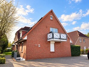 A red brick house with a balcony, a number '24' on the wall, and a paved driveway. - Möwe 4 - bright vacation apartment close to the beach for up to 4 people - Hamburger Str. (Cuxhaven)