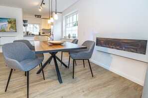 A modern dining area with a wooden table, four grey upholstered chairs, and pendant lighting. - Wanlik Hüs I - 3-room vacation apartment, for max. 3 persons with terrace. (Sylt)