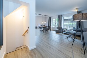 Un salon moderne avec un coin repas, de grandes fenêtres et un escalier.