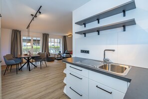 Une cuisine moderne dotée d’un évier encastré, de meubles blancs et d’un coin repas avec une table et des chaises.
