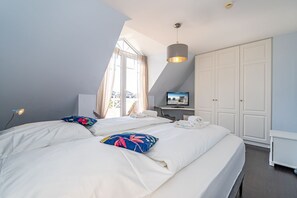 Habitación de hotel con dos camas, televisión, armario y ventana con cortinas.