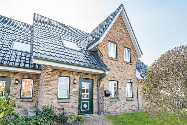 A two-story house with a sloped roof, brick exterior, and a green door.