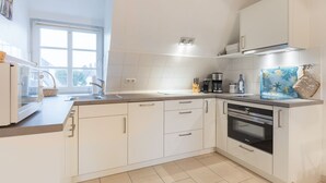 Una cucina moderna con mobili bianchi, forno integrato e un'ampia finestra che fa entrare luce naturale.