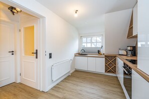 A modern kitchen with white cabinetry, a built-in oven, and a window above the sink.