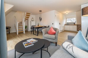Een moderne woonkamer met een trap, een eethoek en een keuken.