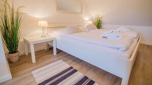 Une chambre à coucher avec un lit, des tables de chevet, des lampes et une plante en pot.