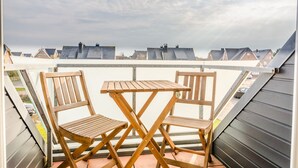 Une terrasse sur le toit, avec deux chaises en bois et une table, d’où l’on peut admirer une rangée de maisons.
