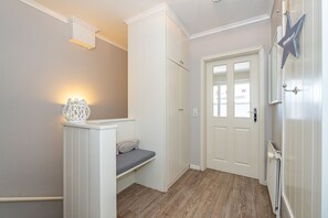 A hallway with a bench, a door with a window, and a wall-mounted star decoration.