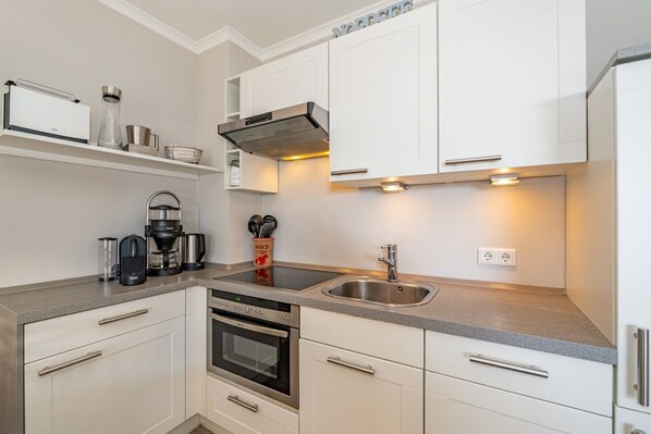 A modern kitchen with white cabinets, stainless steel appliances, and a built-in oven.