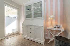 Ein Zimmer mit einem weißen Schrank mit Glastüren, einem kleinen Tisch mit Lampe und einem Teppich auf dem Boden.
