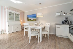 A modern kitchen with white cabinetry, a dining table with chairs, and a pendant light.