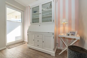 A room with a white cabinet with glass doors, a small table with a lamp, and a rug on the floor. - Schloss am Meer, App. 5 "Strandläufer" - 3-room vacation apartment with terrace - (Wenningstedt-Braderup (Sylt))