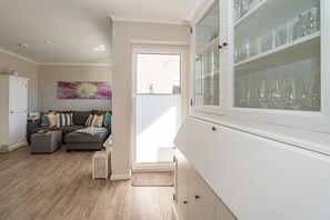 A modern kitchen with white cabinetry, a built-in glass display case, and a wooden floor.