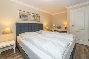 Una habitación de hotel con una cama grande, dos lámparas de noche, una mesita de noche, un espejo y una puerta.