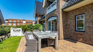 En terrasse med et bord og stole, en murstensmur og en port.