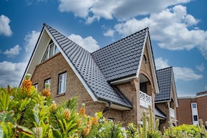 Ein zweistöckiges Haus mit steiler Satteldachform, Ziegelhausfassade und einem kleinen Balkon.