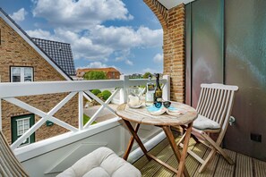 Ein Balkon mit Tisch für zwei Personen, einem Stuhl und einer Champagnerflasche.