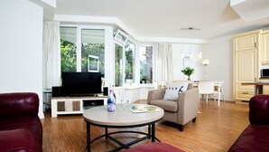 Una sala de estar moderna con un televisor de pantalla plana, una mesa redonda de centro y sofás de cuero rojo.