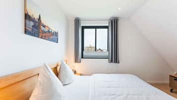 A bedroom with a bed, a nightstand, a window with curtains, and a cityscape painting on the wall.