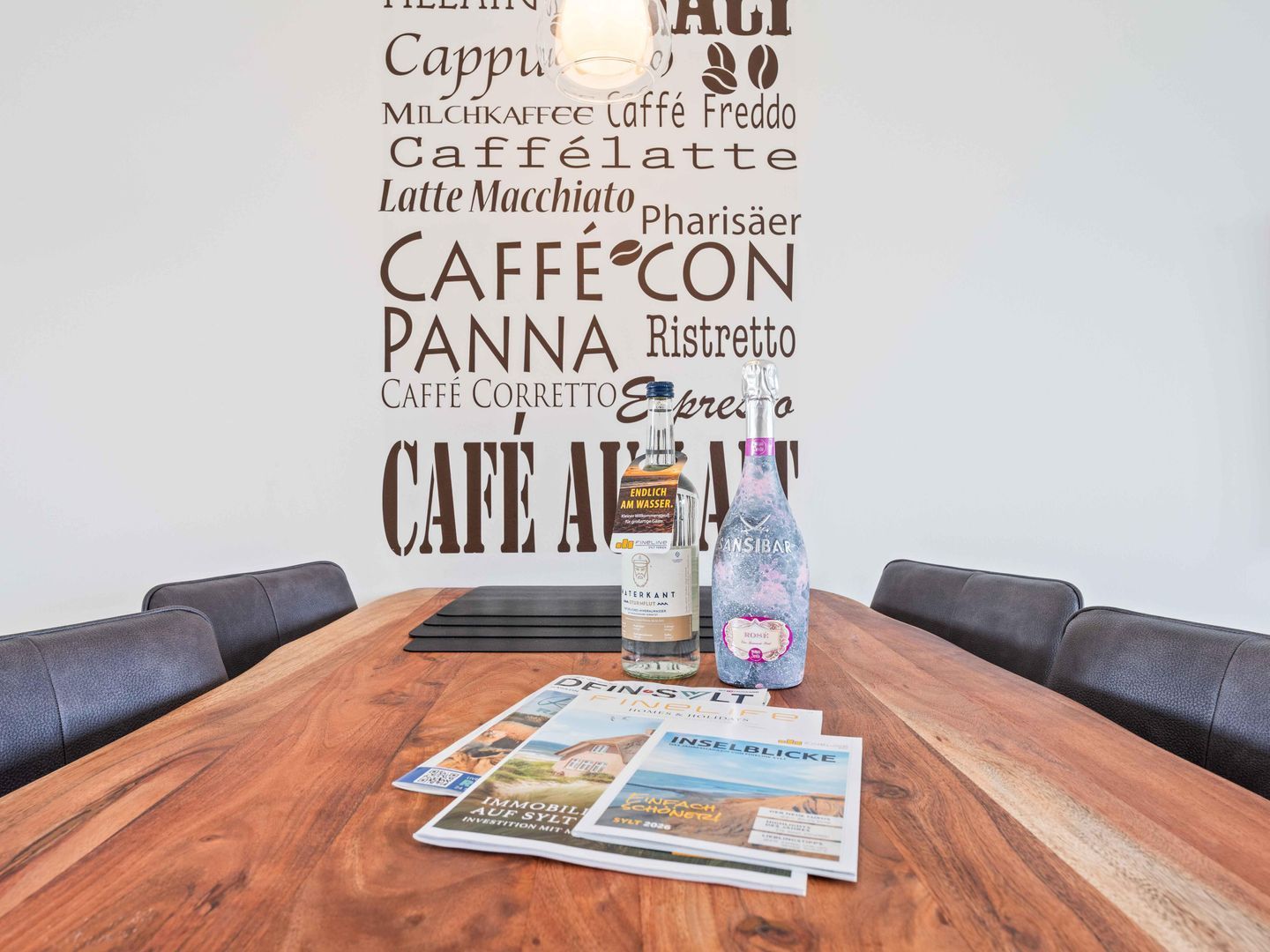 Une table de conférence avec des magazines, une bouteille d’eau et une bouteille d’alcool.