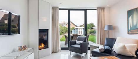 Una sala de estar moderna con chimenea, un sofá, una mesa de centro y un televisor.
