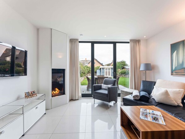 Una sala de estar moderna con chimenea, un sofá, una mesa de centro y un televisor.