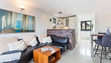 A modern living room with a leather sofa, a coffee table, and a brick accent wall.