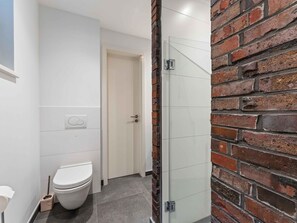 Un baño con inodoro, cabina de ducha de vidrio y puerta blanca.