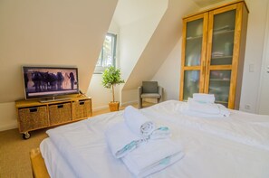 Quarto de hotel com televisão, cama com toalhas, uma cadeira e um guarda-roupa.